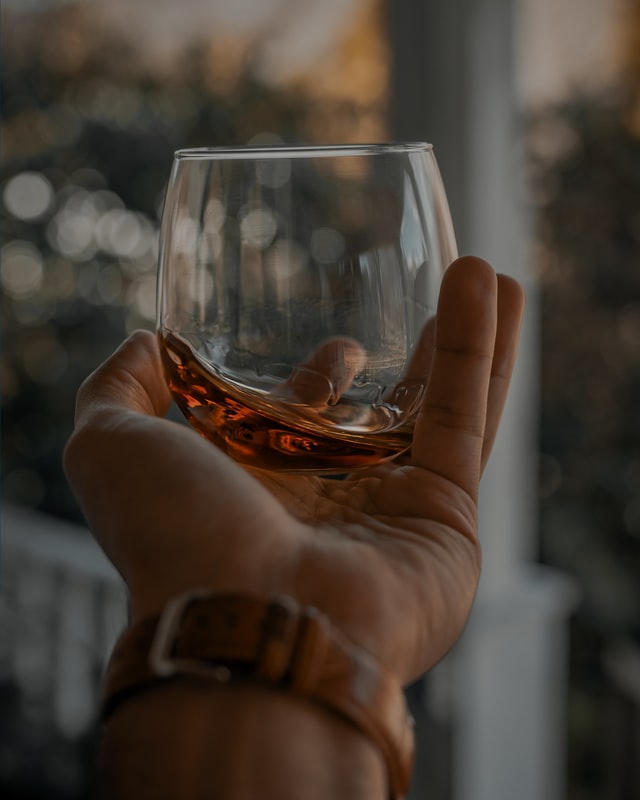 man holding a glass of bourbon vs scotch
