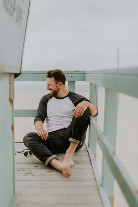 man sitting down laughing, self care for men
